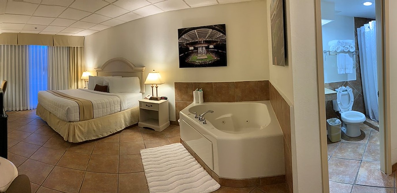 A hotel room with a king bed, a jacuzzi and bathroom