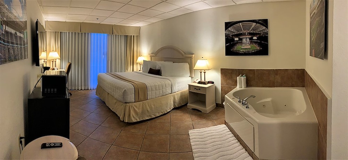 A hotel room with a king bed, a jacuzzi, a TV and a patio.